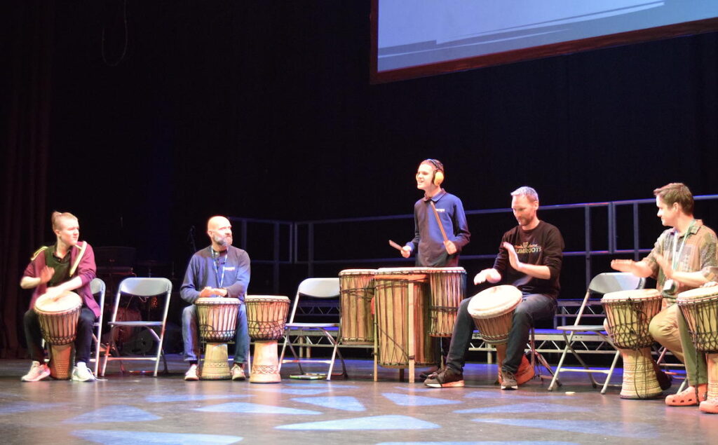 3 men and two boys performing African drums on a stage