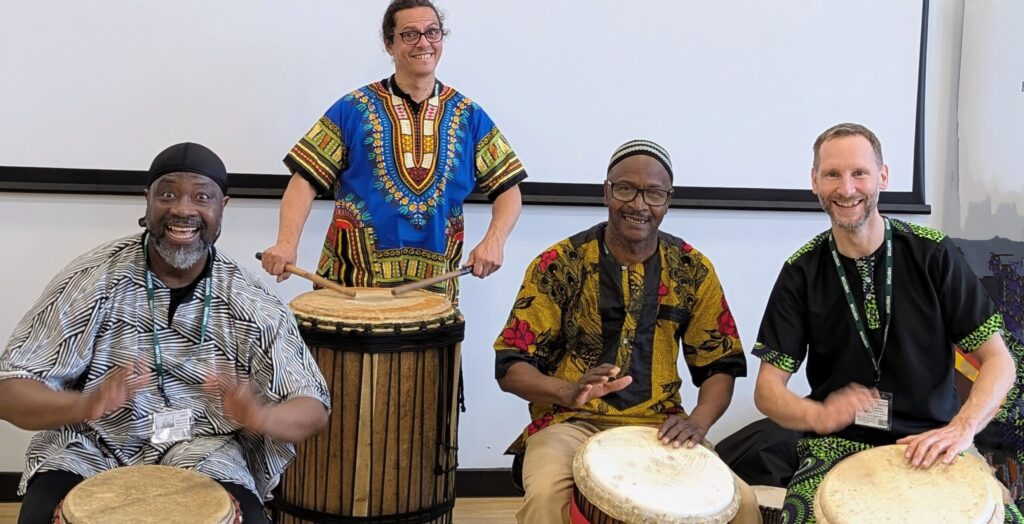 Four men playing African drums